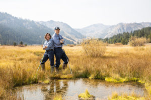 Employees posing in field in front of a pond with mountains in the background